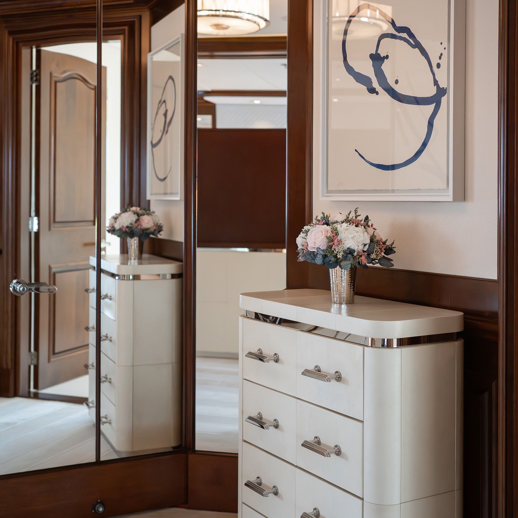 Preserved flower arrangement on a white dresser with silver accents in master bedroom on a yacht.
