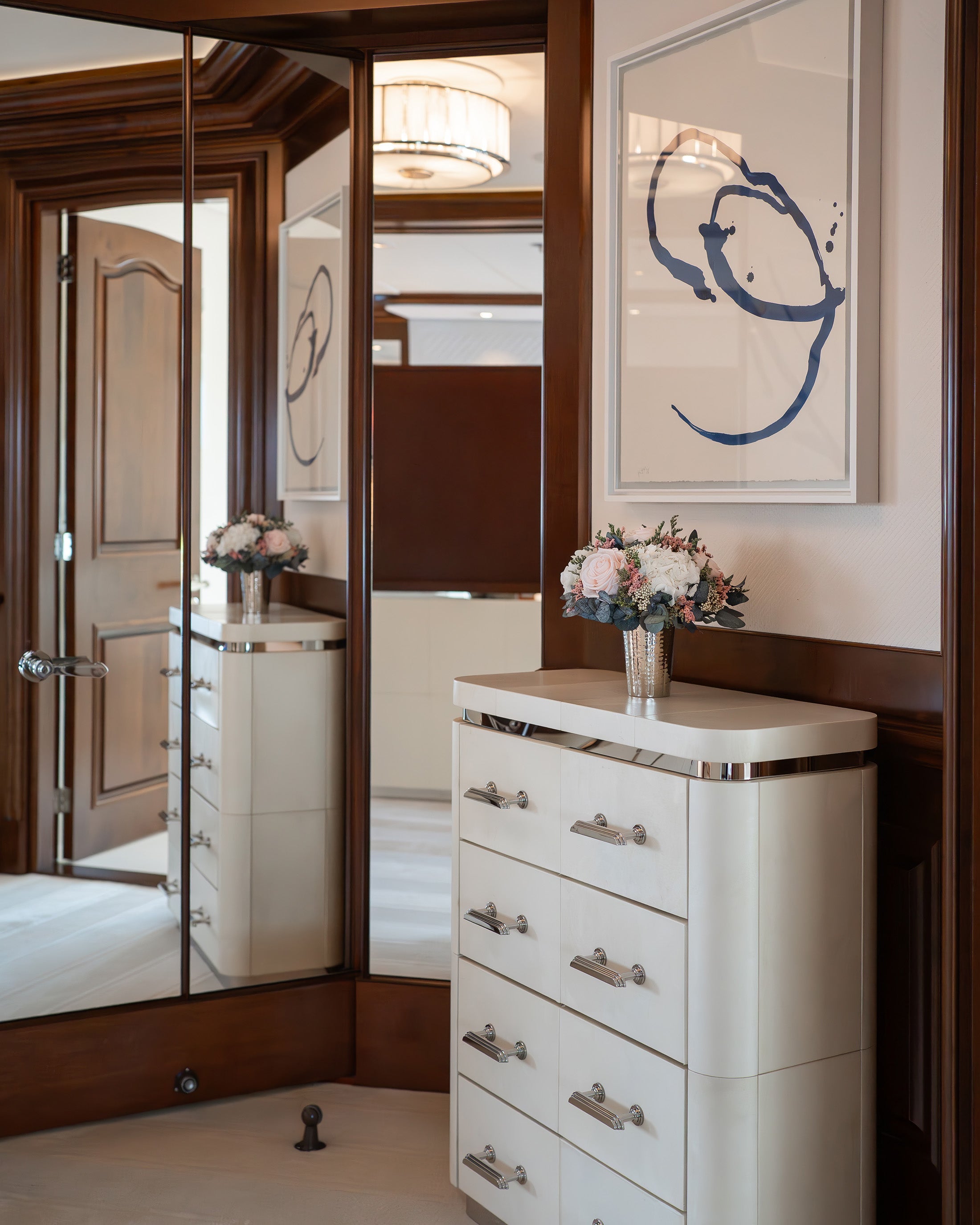 Preserved flower arrangement on a white dresser with silver accents in master bedroom on a yacht.